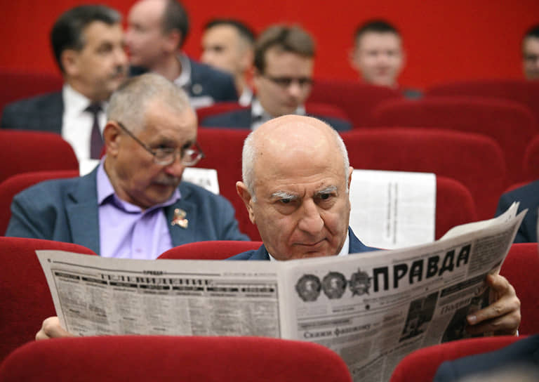 Участник читает газету в зале перед началом пленума