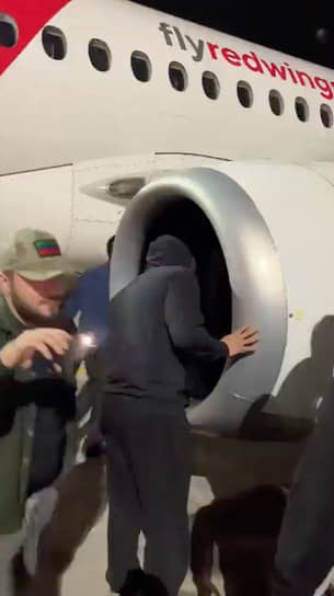 Один из участников антисемитских выступлений в аэропорту Махачкалы заглядывает в турбину самолета