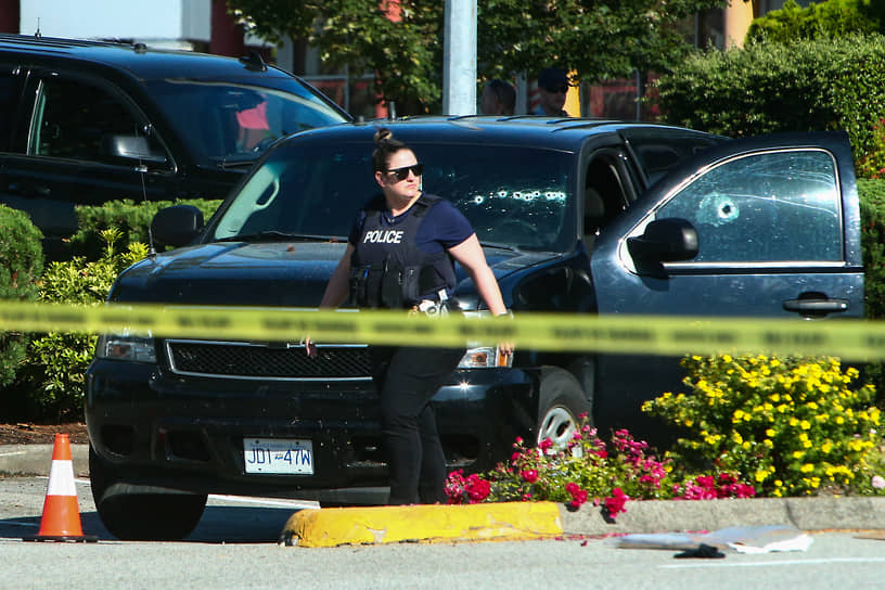 Полицейский на фоне автомобиля с пулевыми отверстиями в канадском Лэнгли 