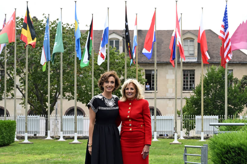 Первая леди США Джилл Байден (справа) и гендиректор ЮНЕСКО Одре Азуле позируют на фоне флагов стран, входящих в ЮНЕСКО