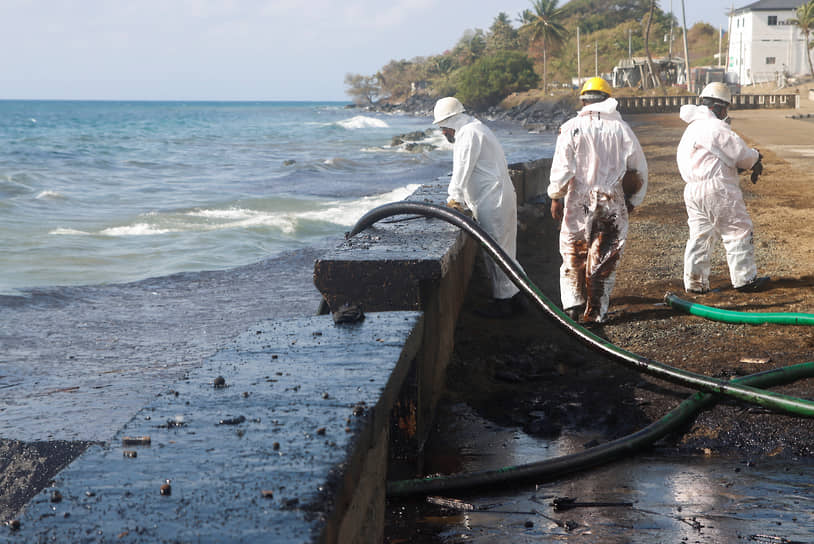 Работники экологической службы отсасывают нефть с места разлива