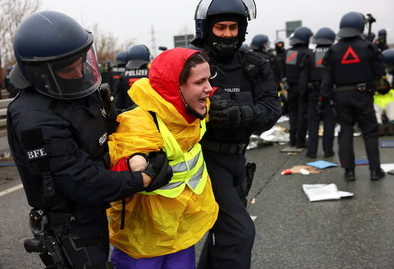 Полицейские уводят демонстрантку с улицы во время акции протеста