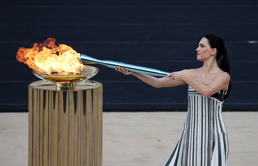 Греческая актриса Мэри Мина в наряде верховной жрицы зажигает факел