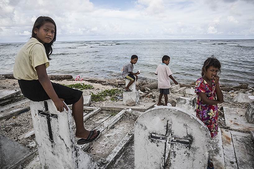 На одном из Маршалловых островов дети играют на кладбище. Из-за береговой эрозии оно частично ушло под воду 