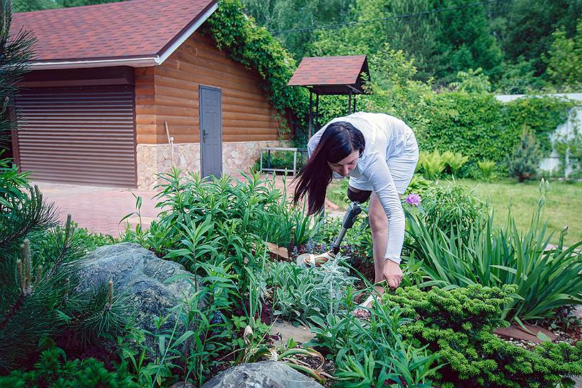 Женщина любит ухаживать за растениями на приусадебном участке