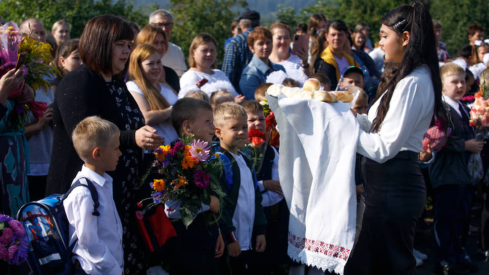 День знаний (1 сентября). Ученица старших классов угощает первоклассников караваем
