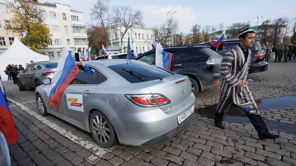  Участник праздничных мероприятий у машины с российским флагом