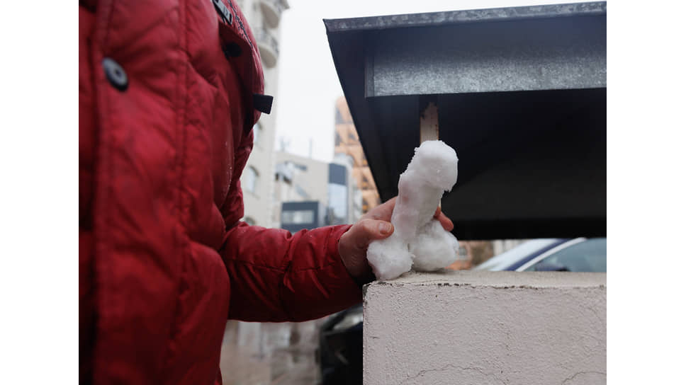 Снежная скульптура мужского полового органа в руках жителя города