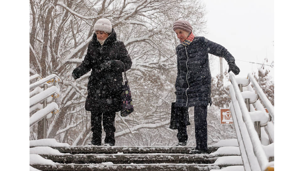 Пожилые женщины спускаются по лестнице во время снегопада 
