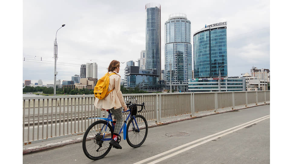 Молодой человек едет на велосипеде по Макаровскому мосту в Екатеринбурге