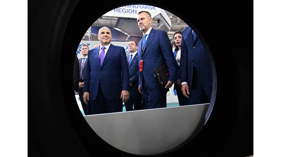 Директор деловой программы выставки &quot;Иннопром&quot; Антон Атрашкин (в центре) и председатель правительства России Михаил Мишустин (слева) во время осмотра выставки