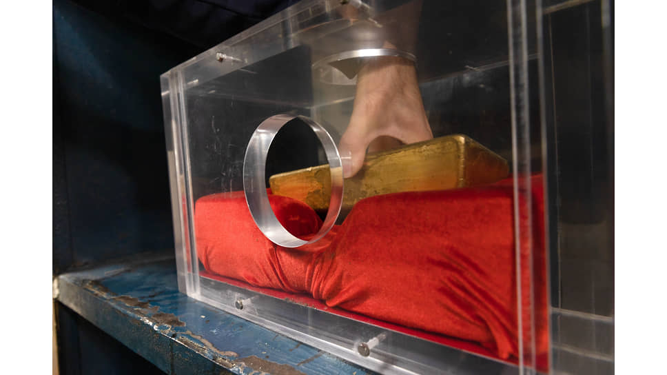 Посетитель экскурсии &quot;Тайны кладовой&quot; у экспоната &quot;Муляж золотого слитка&quot;