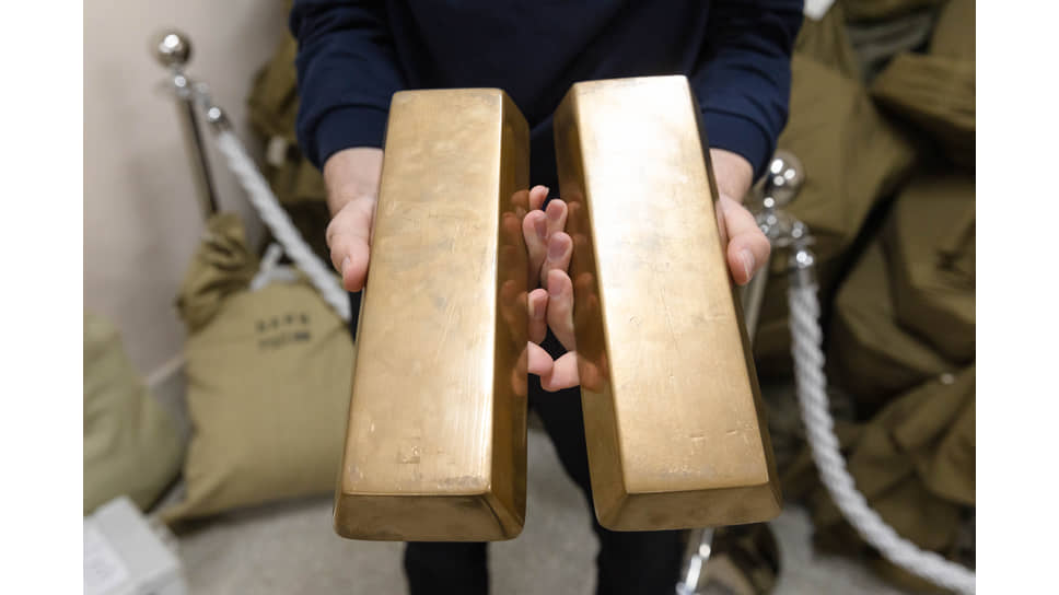 Посетитель экспозиции &quot;Тайны кладовой&quot; с муляжами золотых слитков в руках