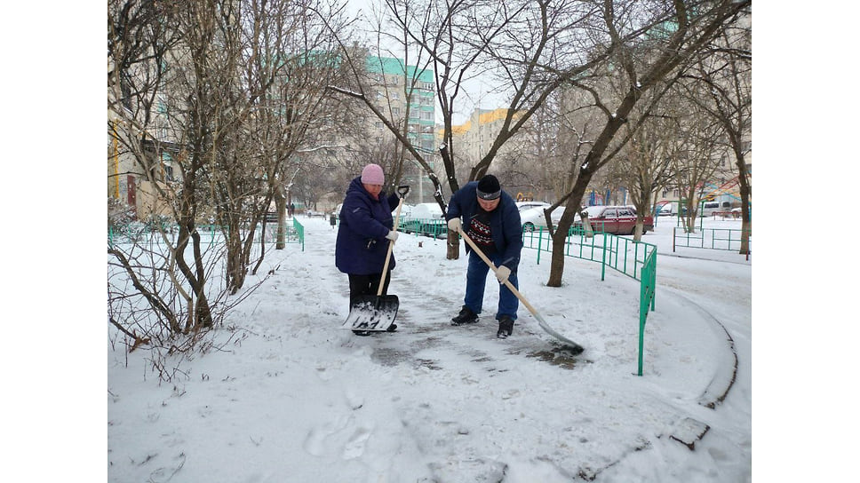 Дворники расчищают двор от снега.
