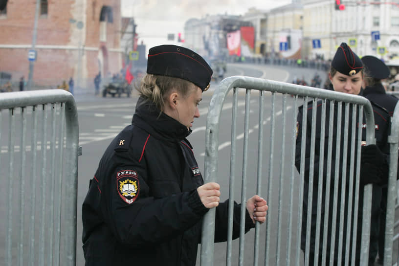 Сотрудница полиции поправляет секцию ограждения вокруг площади Минина