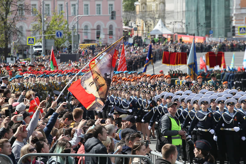 Зрители держат знамя с портретом Сталина во время парада