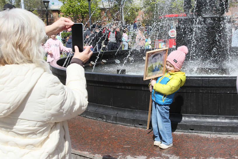 Женщина фотографирует ребенка у фонтана