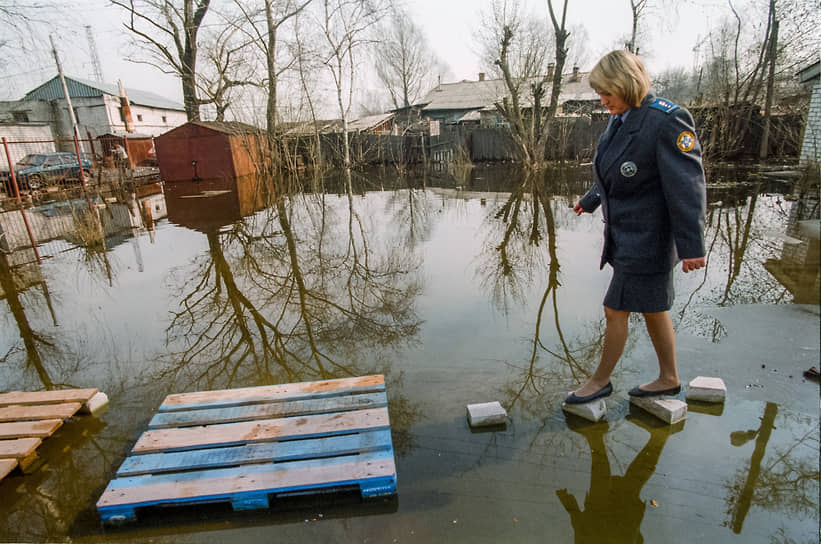 Сотрудница нижегородской ветеринарной таможни переходит затопленный паводком двор