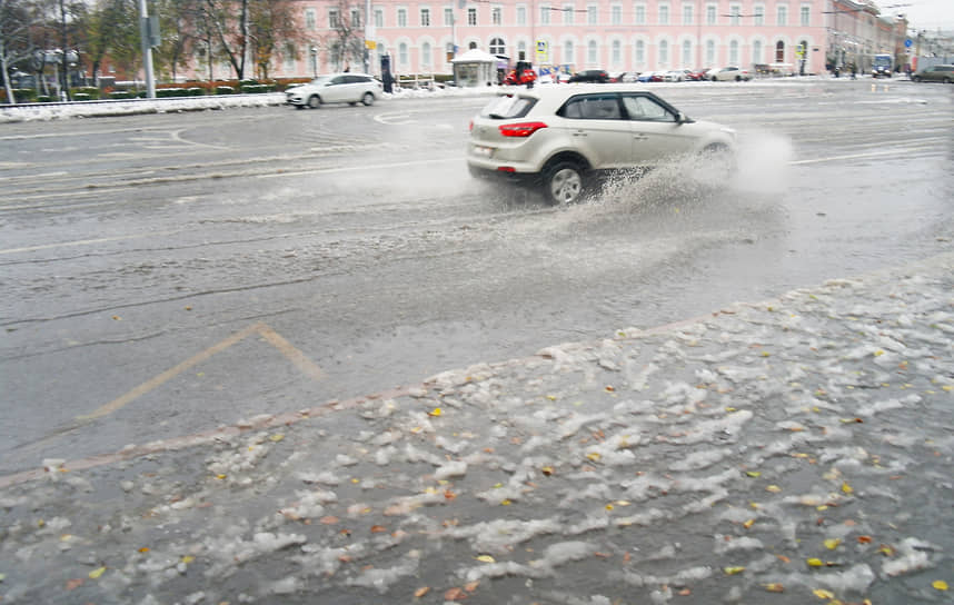 Автомобиль разбрызгивает воду, проезжая по луже