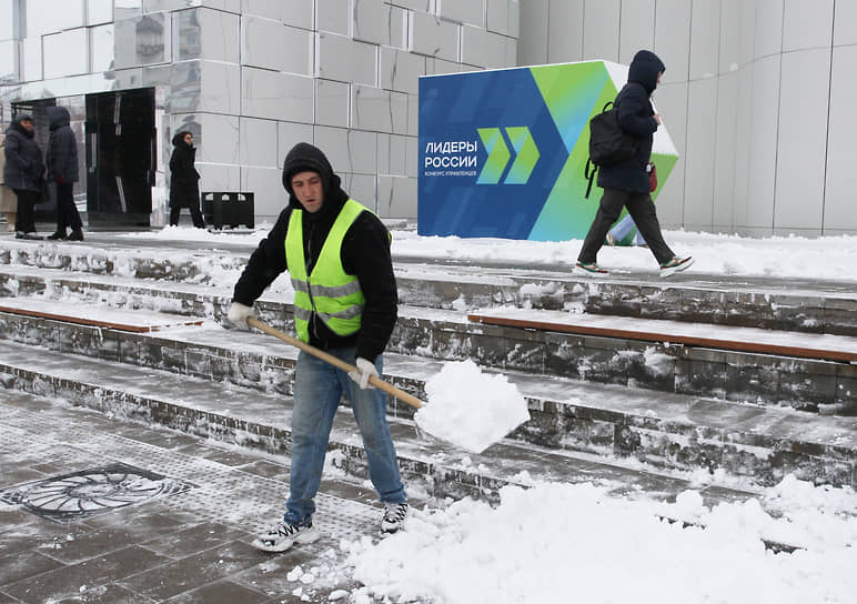 Рабочий убирает снег перед входом в павильон с указателем