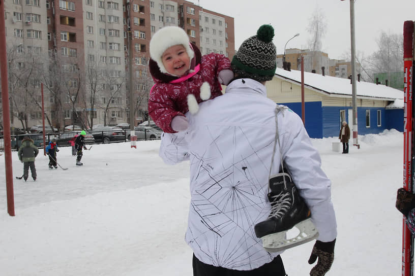 Мужчина с коньками несет на плече ребенка