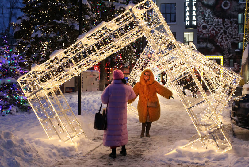 Женщины делают селфи в светящихся арках у здания Волго-Вятского банка Сбербанка России