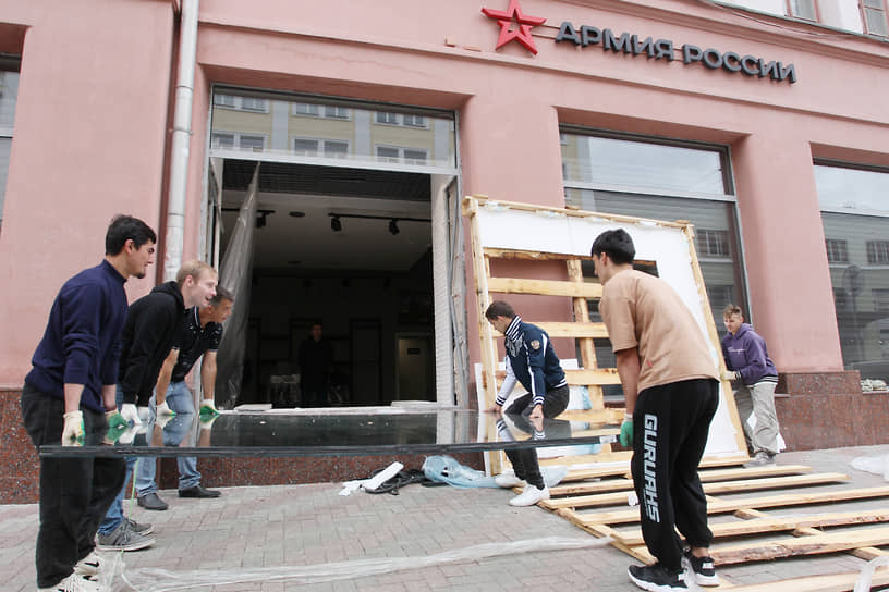 Рабочие меняют разбитое стекло витрины магазина &quot;Армия России&quot;