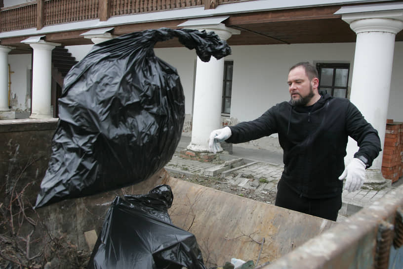 Руководитель управления государственной охраны объектов культурного наследия Нижегородской области Григорий Меламед бросает мешок с мусором в контейнер во время субботника