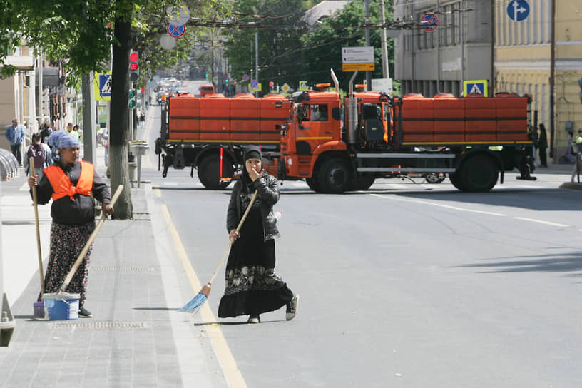 Дворники подметают улицу, перегороженную тяжелой техникой во время празднования Дня Независимости