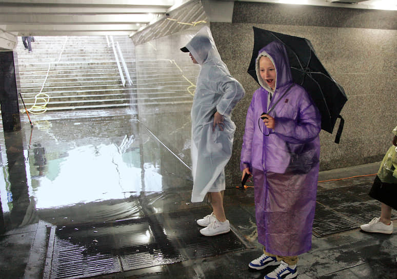 Туристы с зонтами в подземном пешеходном переходе у кремля, залитом водой во время проливного дождя