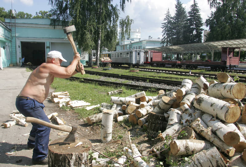 Рабочий рубит дрова для узкоколейного паровоза на станции &quot;Родина&quot; детской железной дороги