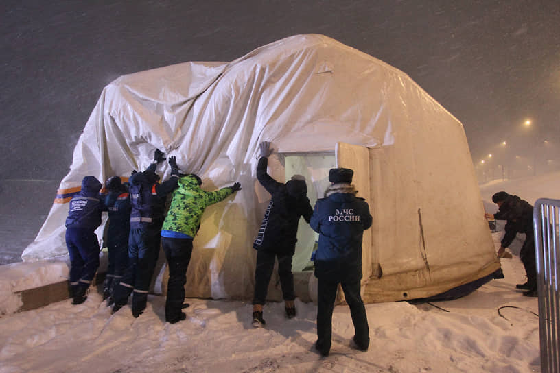 Сотрудники МЧС поднимают палатку с женской раздевалкой, которую сдуло ураганным ветром