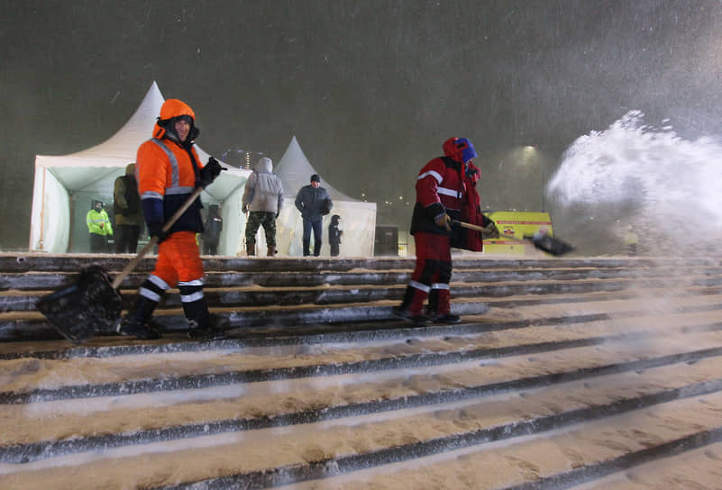 Рабочие сгребают снег с лестницы к набережной
