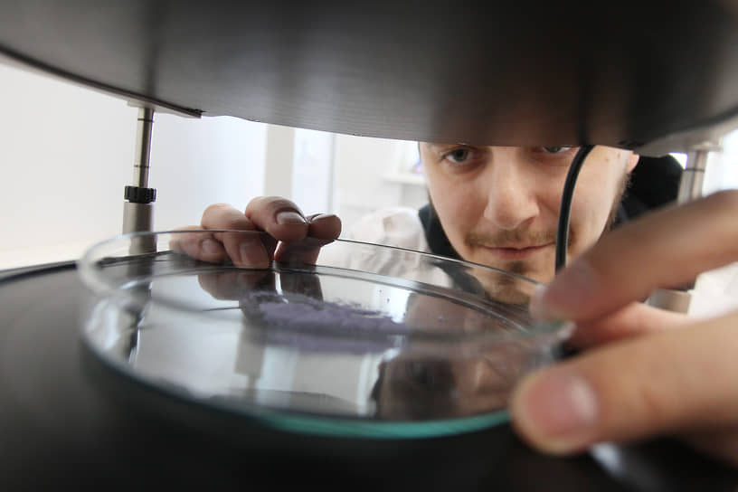 Лаборант устанавливает образец порошка в установку для спекания керамики
