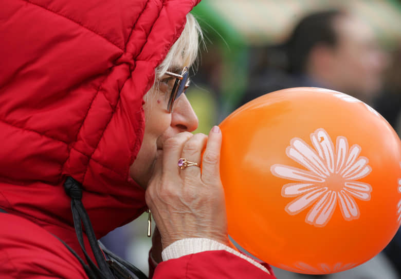 Участница шествия надувает воздушный шарик