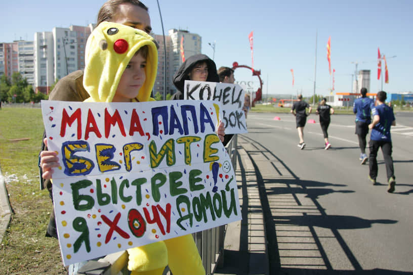 Дети держат плакаты для своих бегущих родителей