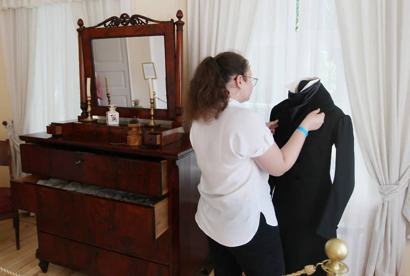 Хранитель музея поправляет сюртук поэта, выставленный в экспозиции