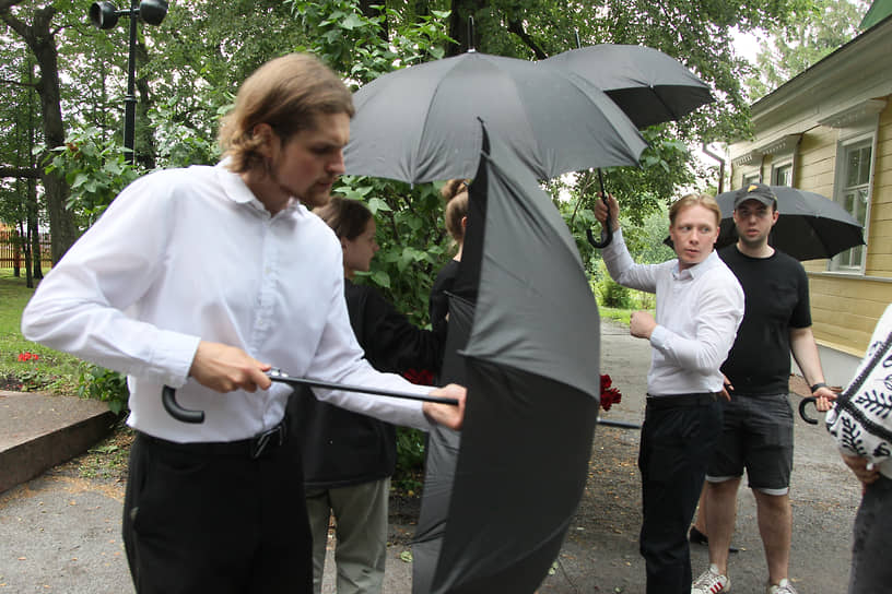 Участники торжеств спасаются от дождя под зонтами