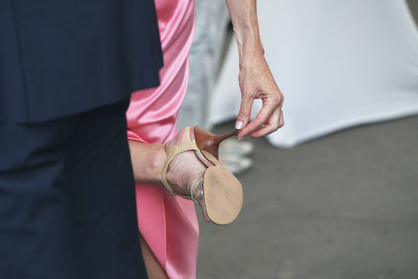 Дама поправляет каблук на туфле