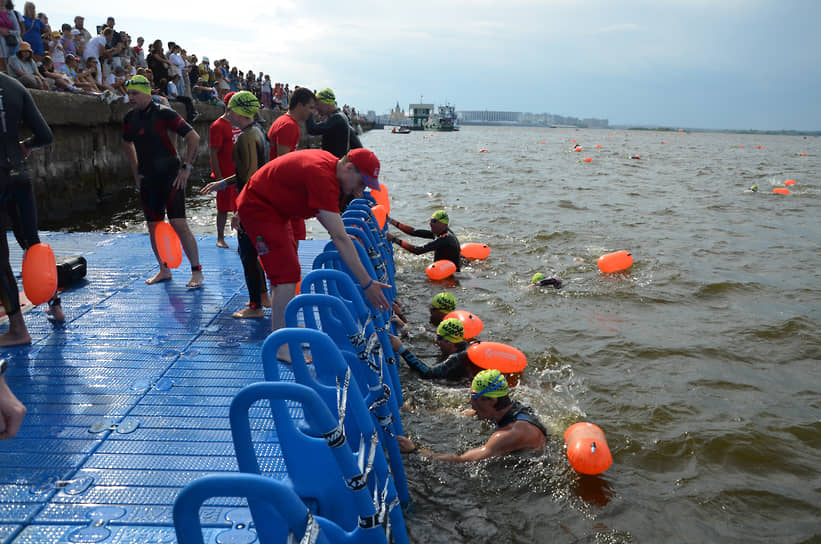 Волонтеры помогают участника заплыва выбраться из воды