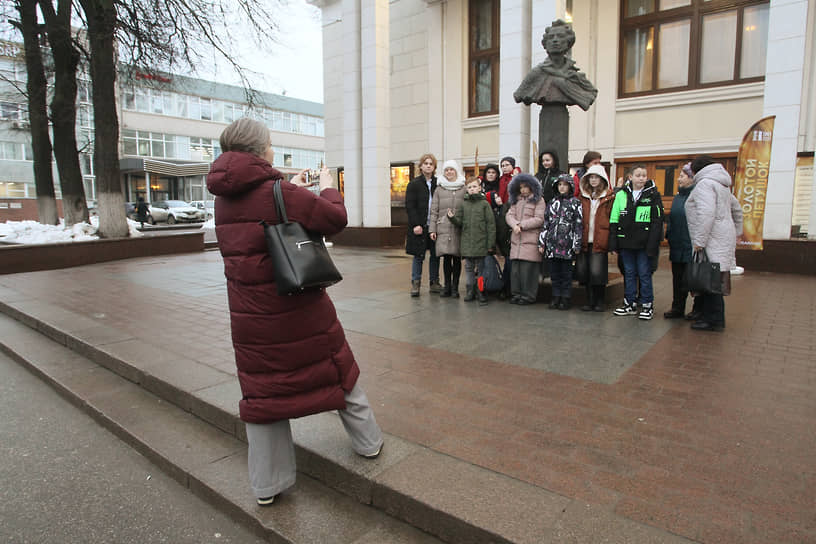 Группа школьников фотографируется у памятника Пушкину перед театром