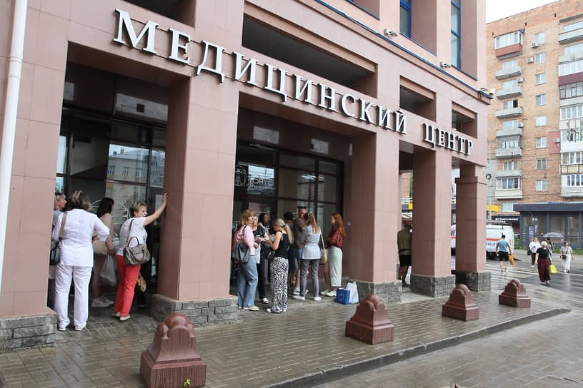 Эвакуированные работники медицинского центра укрываются от дождя