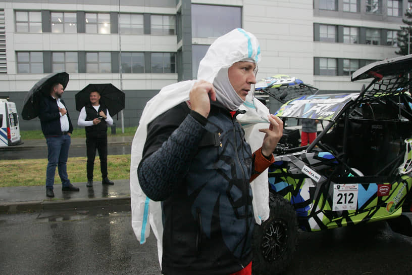 Гонщик надевает непромокаемый костюм