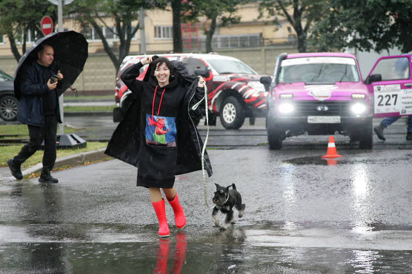 Девушка с собакой надевает дождевик