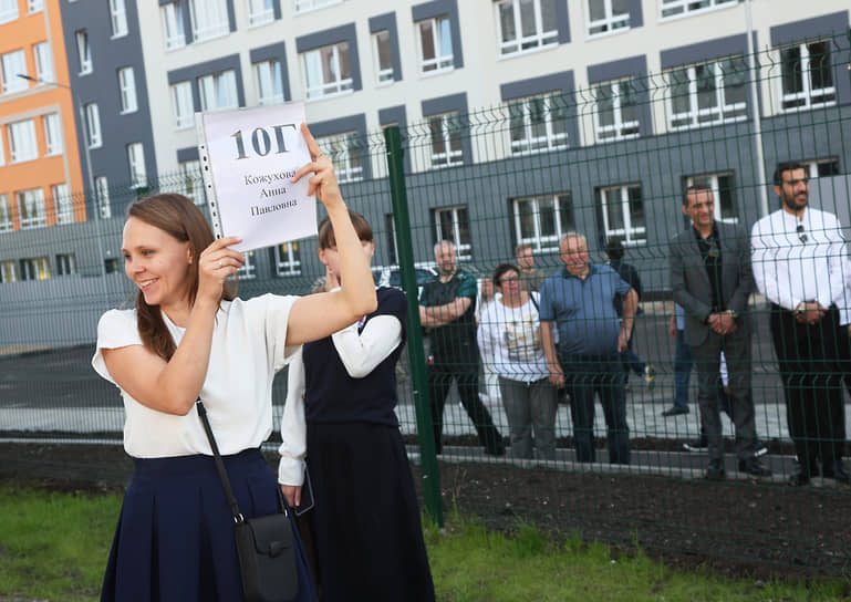 Преподаватель держит табличку с номером класса «10Г»