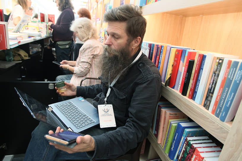 Мужчина с ноутбуком сидит у витрины с книгами