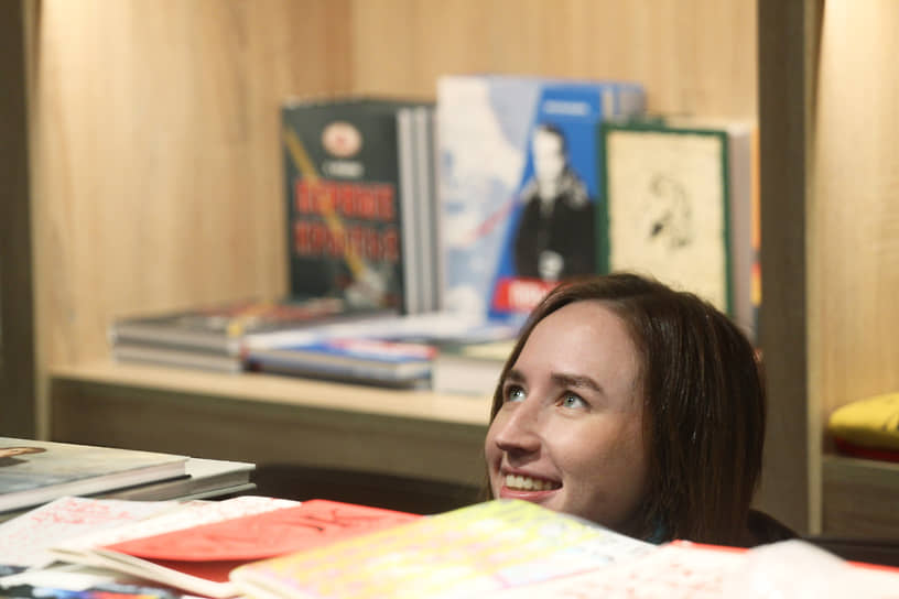 Девушка ищет книги под прилавком