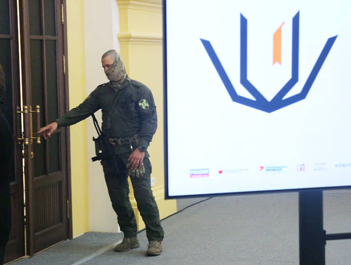 Охранник в армейском камуфляже у входа в зал ярмарки