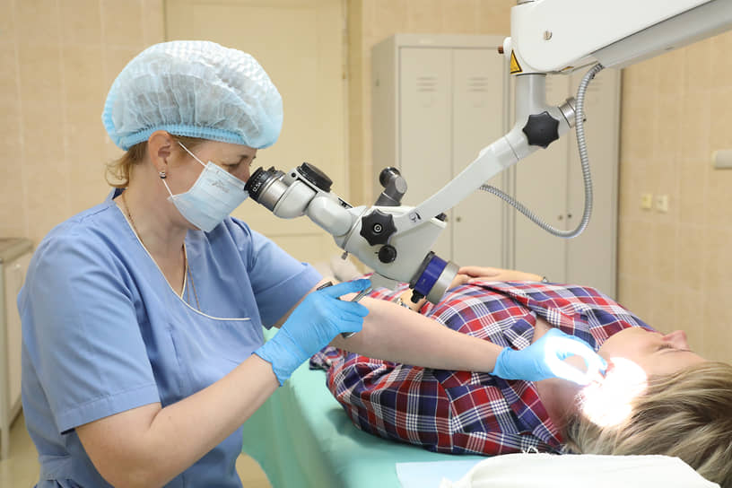 Смотровой ЛОР-кабинет. Врач осматривает ухо пациента с помощью микроскопа
