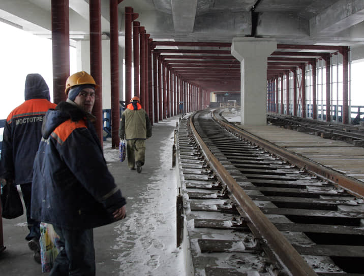 Март 2012 года. Рабочие метростроя идут вдоль проложенных железнодорожных путей по метромосту